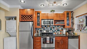Une cuisine compacte avec des meubles en bois, des appareils électroménagers en acier inoxydable et un dosseret carrelé.
