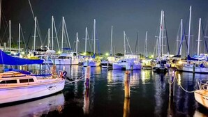 Un port de plaisance de nuit, où de nombreux voiliers sont amarrés.