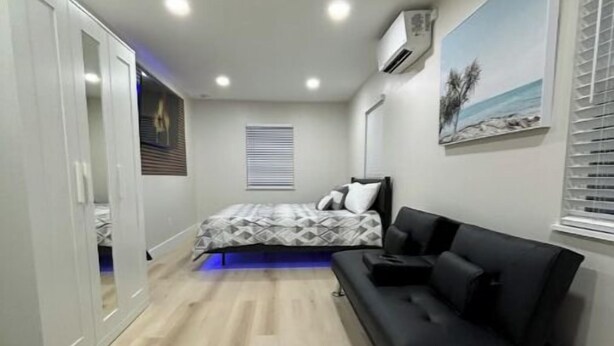 A modern bedroom with a bed, a black sofa, and a wardrobe. - Private studio near downtown (St. Augustine)