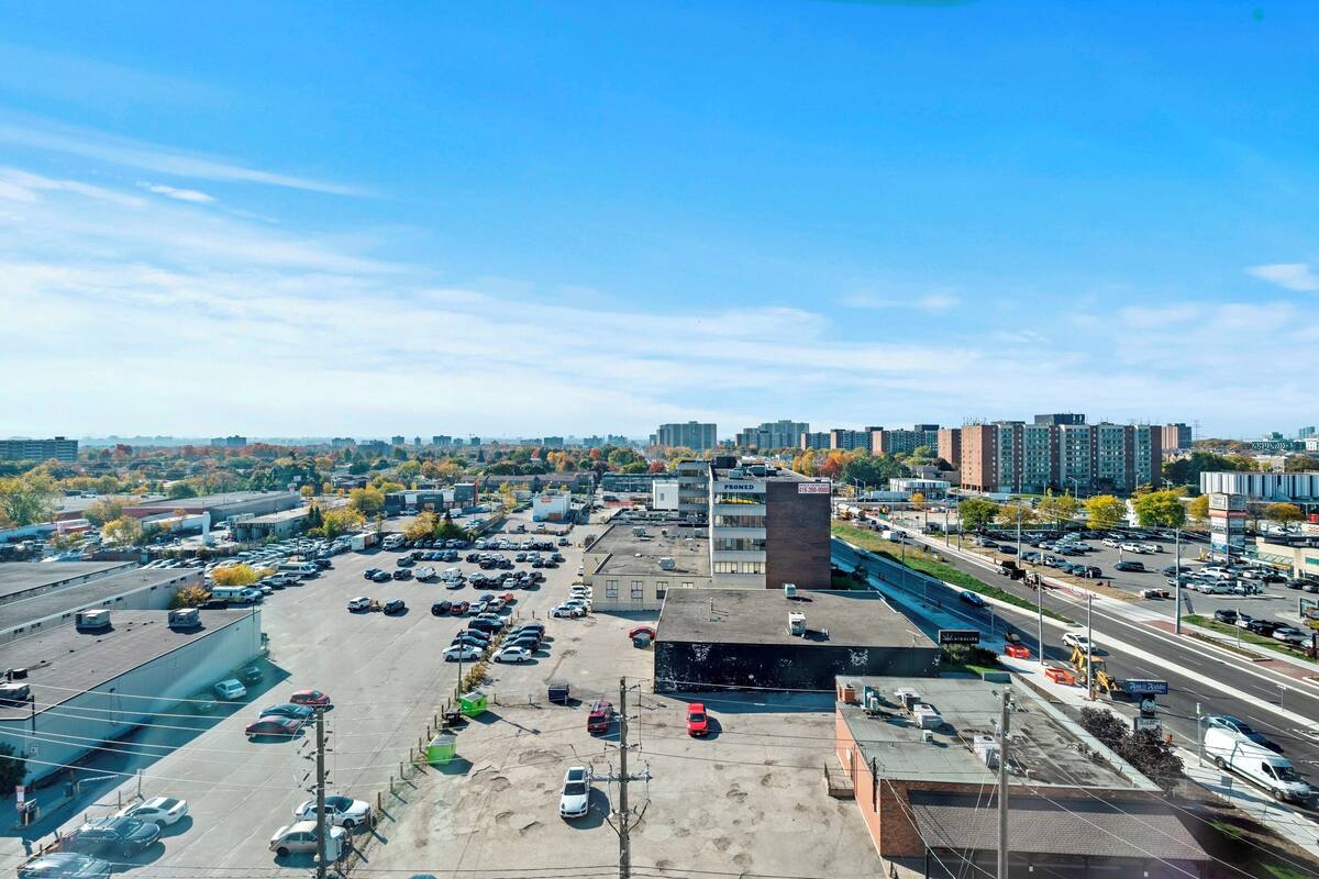 An aerial view of a parking lot with multiple cars, a building labeled "PROMED," and a highway in the background.