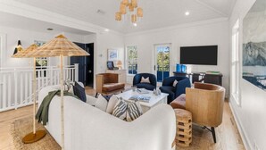 A spacious living room with a white sofa, two armchairs, a coffee table, and a hanging light fixture.