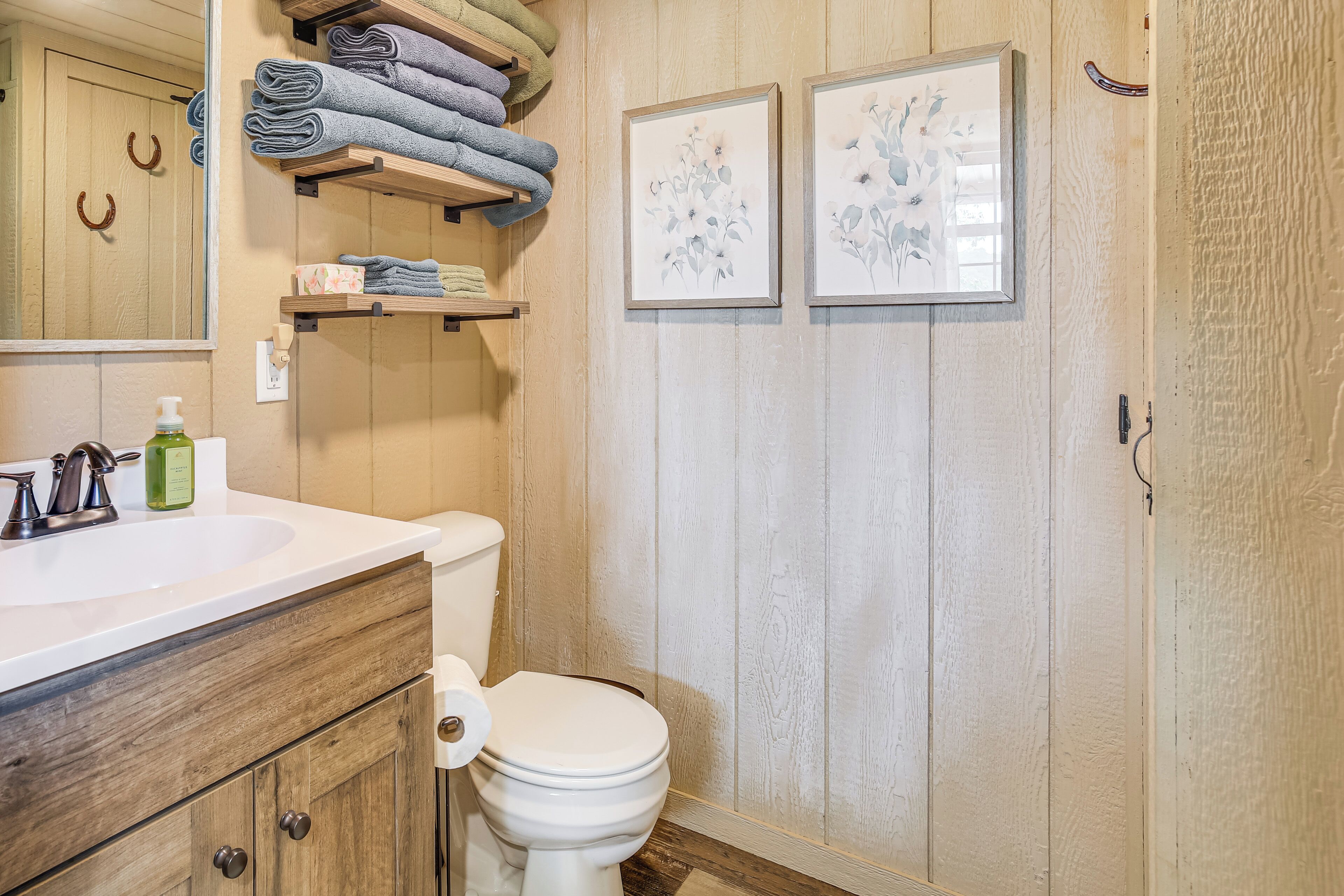 Un baño con tocador de madera, un inodoro y un perchero con toallas dobladas.