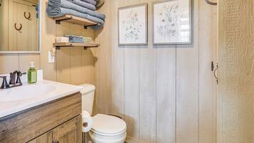 Un baño con tocador de madera, un inodoro y un perchero con toallas dobladas.