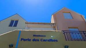 A building with a sign reading "Résidence Perle des Caraïbes" against a clear blue sky. - Chez Marguerite by Magcar (Le Gosier)