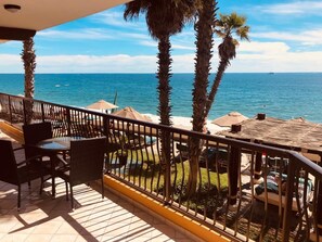 Un balcon aménagé avec du mobilier d’extérieur, des palmiers et une vue sur la mer.