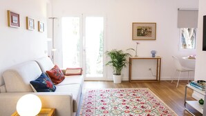 A living room with a sofa, a coffee table, a potted plant, a rug, and a small side table.