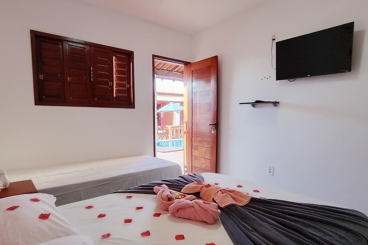 A hotel room with a bed, a TV, a wooden door, and a view of the outside.