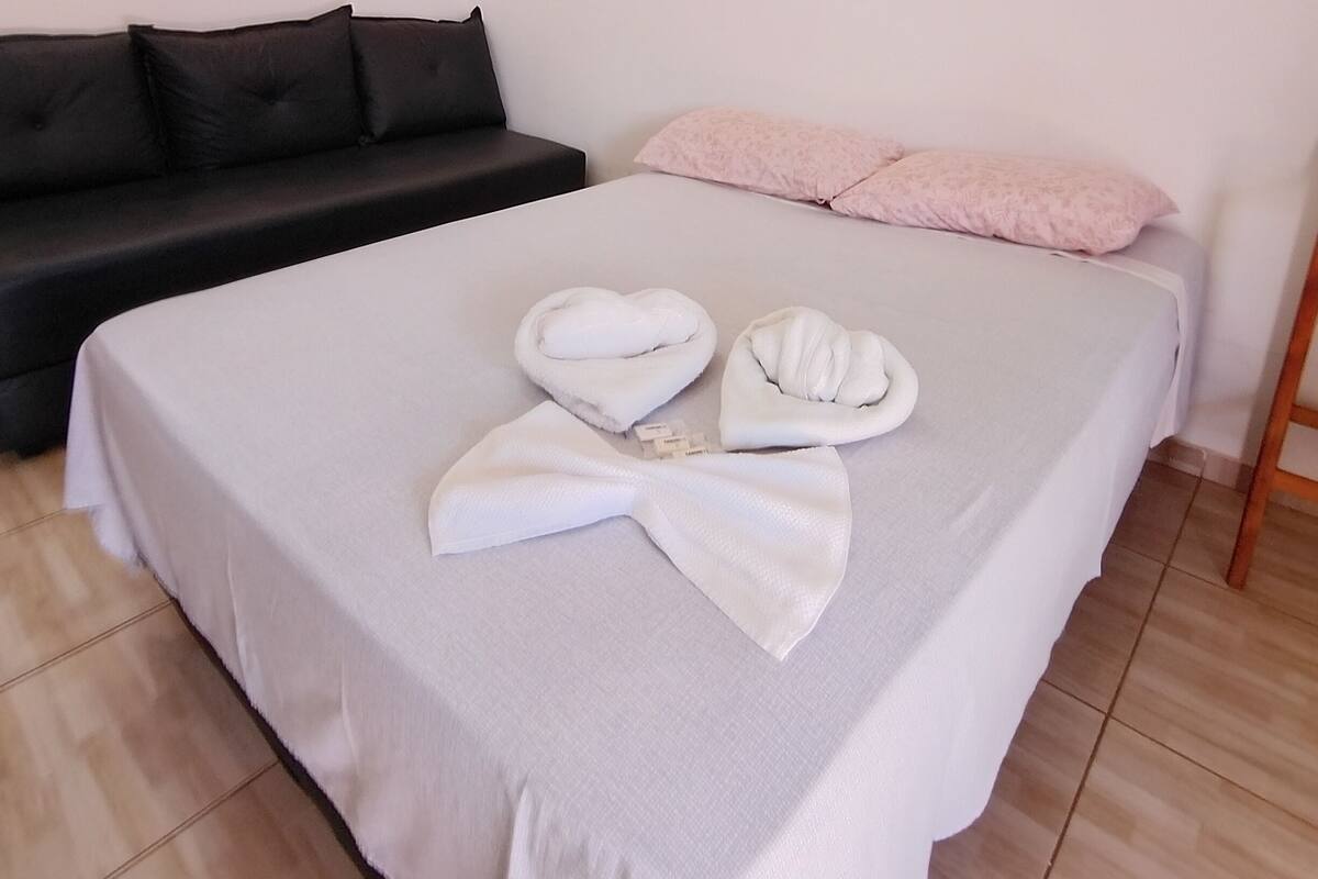 A hotel room with a bed, a black sofa, and a wooden ladder.