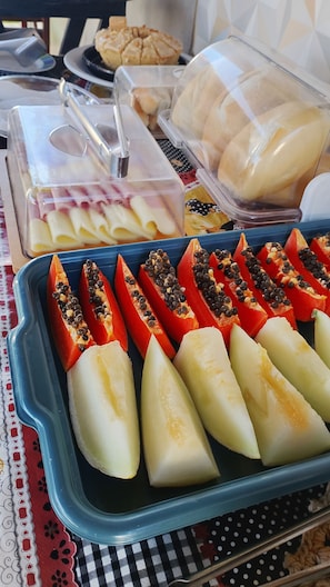 Ein Buffet mit verschiedenen Speisen, darunter Obstscheiben, eine Schale mit weißer Substanz und eine blaue Tablett mit rot-weißen Gegenständen.