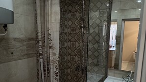 A bathroom with a glass-enclosed shower, a white sink, and a mirror.