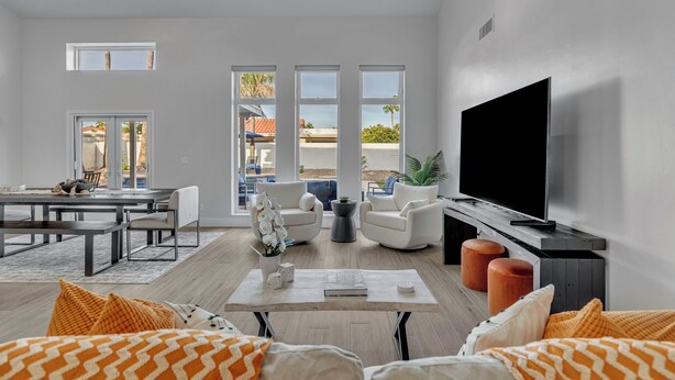A spacious living room with a large flat-screen TV, a dining area with a table and chairs, and a seating area with sofas and a coffee table. - Modern and Classy 4 Bdrm N. Scottsdale Retreat! (Scottsdale)