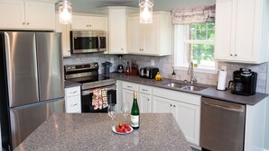 Una cocina moderna con electrodomésticos de acero inoxidable, armarios blancos y encimera de granito.