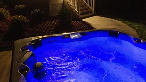 Un jacuzzi con luz azul, una casa con balcón y una escalera.