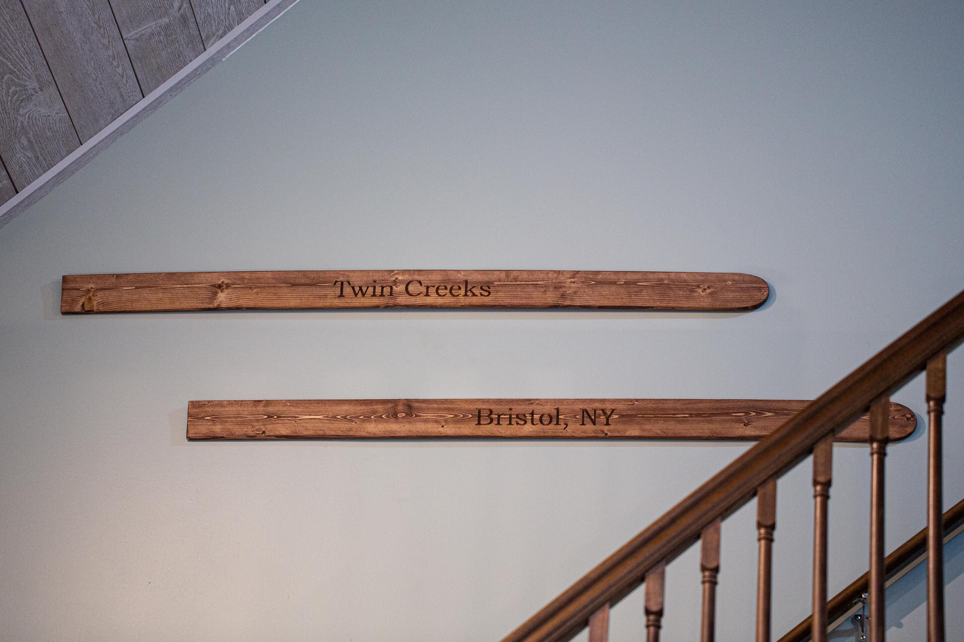 Wooden signs on a staircase railing with the text "Twin Creeks" and "Bristol, NY".