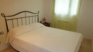 A single bed with a metal headboard in a room with wooden flooring. - Ten minutes from the beach, luxury apartment in the center of Rosas (Roses)