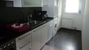 A compact kitchen with a sink, stove, and washing machine. - Ten minutes from the beach, luxury apartment in the center of Rosas (Roses)