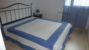 A bedroom with a bed, a nightstand, a lamp, and a window with curtains. - Ten minutes from the beach, luxury apartment in the center of Rosas (Roses)