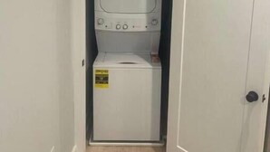 A laundry room with a washer and dryer, a door, and a light switch on the wall.