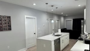 A modern kitchen with white cabinetry, a central island with a sink, and pendant lighting.