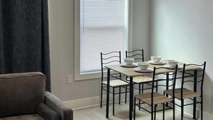 A dining area with a table set for four, four chairs, and a window with blinds.