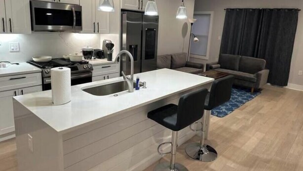 A modern kitchen with white cabinetry, stainless steel appliances, and a central island with bar stools.