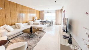 A modern living room with a sectional sofa, a coffee table, and a TV on a stand. - Paradis Citadin (La Marsa)