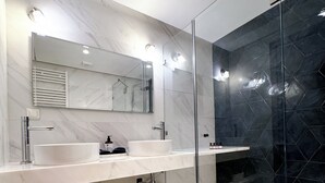 A modern bathroom with two sinks, a large mirror, and a glass-enclosed shower area. - Paradis Citadin (La Marsa)