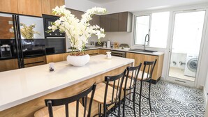 A modern kitchen with a central island, black chairs, and a potted orchid. - Paradis Citadin (La Marsa)