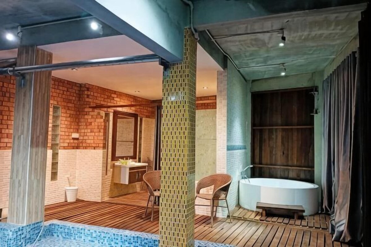A modern bathroom with a bathtub, a shower area, and a seating area with chairs.