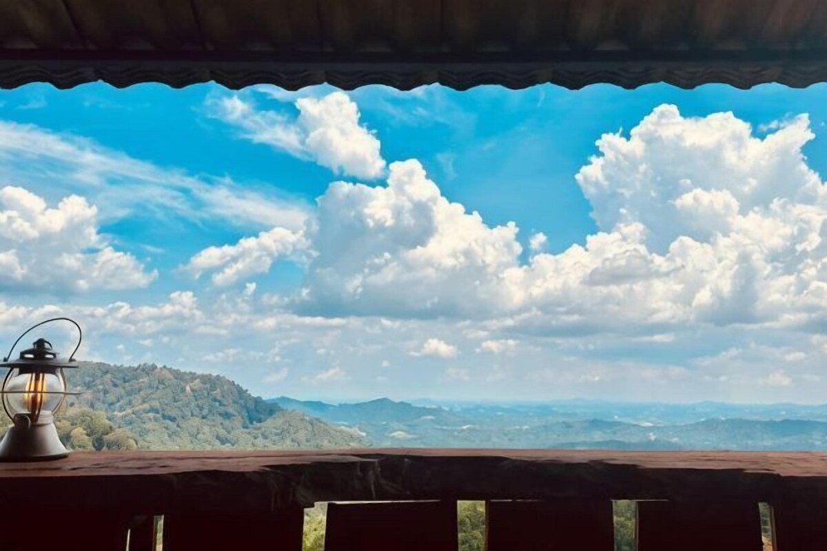 A table with a lantern and a view of a mountainous landscape under a clear sky.