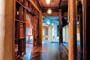 Un couloir en bois avec un luminaire au plafond, des murs en bois et une vue sur une autre pièce.