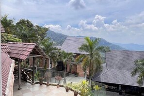 A residential area with a balcony, potted plants, and a mountain view. - Sankara Garden (Seremban)