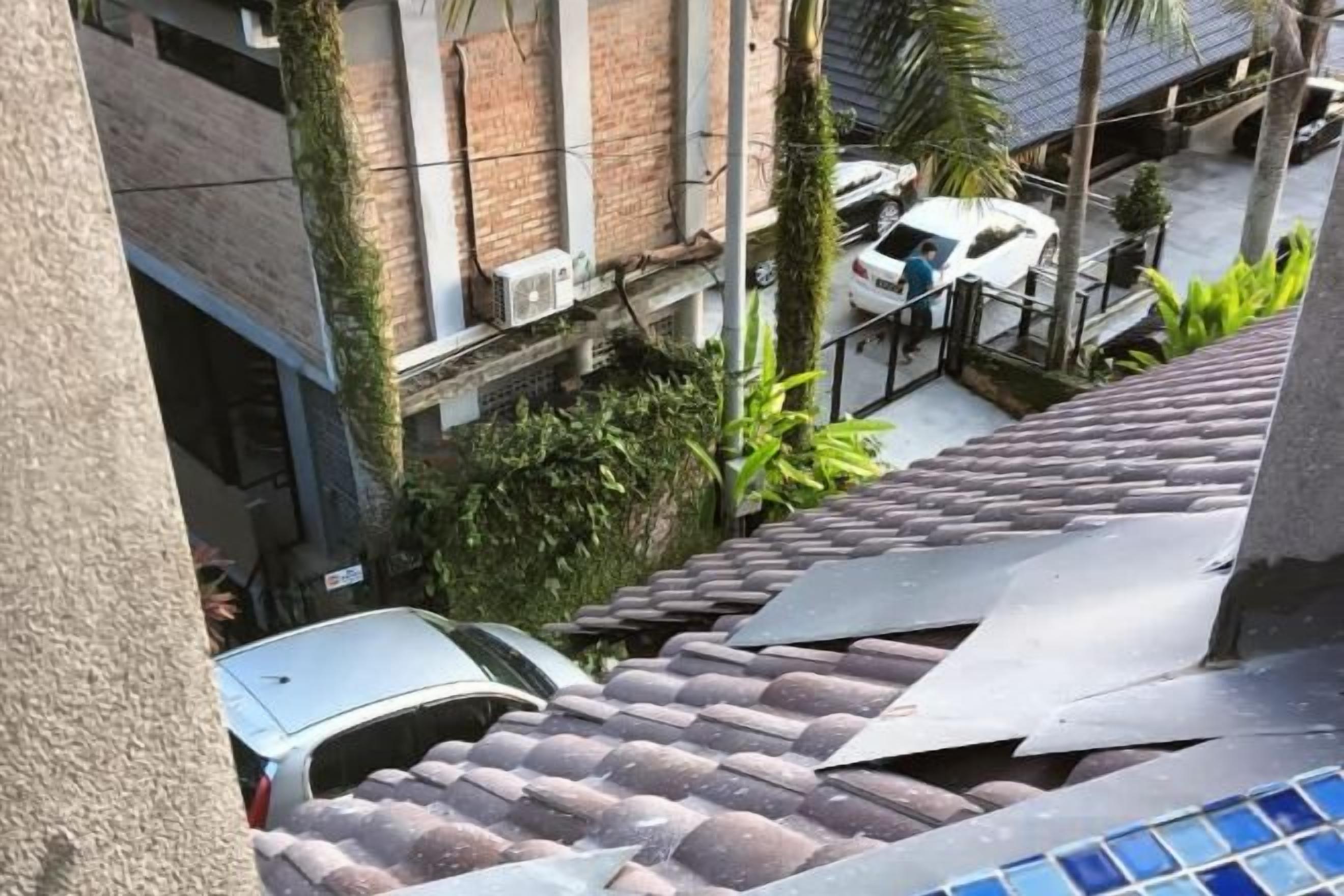 A residential area with a tiled roof, a parked car, and a white vehicle in the background.