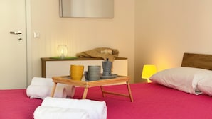 Ein Hotelzimmer mit einem Bett, einem Nachttisch mit Lampe sowie einem Tablett mit Handtüchern und einer Kaffeemaschine.