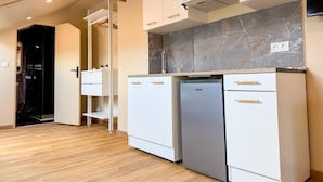 Una cocina compacta con armarios blancos, estufa integrada y un refrigerador.