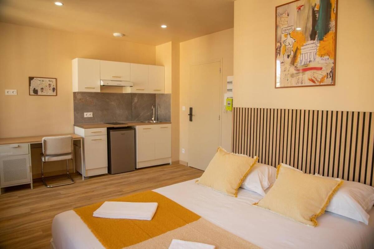 A hotel room with a bed, a desk, and a kitchenette.