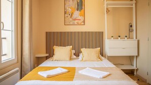 Habitación de hotel con cama, mesita de noche, una obra de arte en la pared y un armario blanco.