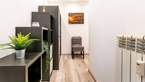 A narrow hallway with a radiator, a chair, and a framed picture of the Colosseum.