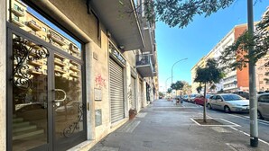 A street view with a building featuring a large glass door and a metal railing.