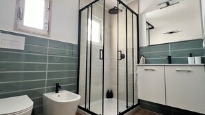 A bathroom with a glass-enclosed shower, a toilet, and a sink with a mirror above. - Lucky Corner - Elegant Stay (Taranto)