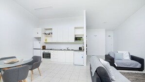 A compact living space with a kitchenette, a dining area, and a seating area with a sofa and a small table.