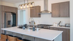 A modern kitchen with a central island, stainless steel appliances, wooden cabinets, and a pendant light fixture. - Muskoka Hills - Four Bedroom Cottage, Sleeps 8 (Huntsville)