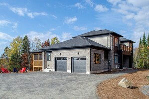 Une maison moderne à deux étages, dotée d’un garage, d’un porche couvert et d’une allée gravillonnée.