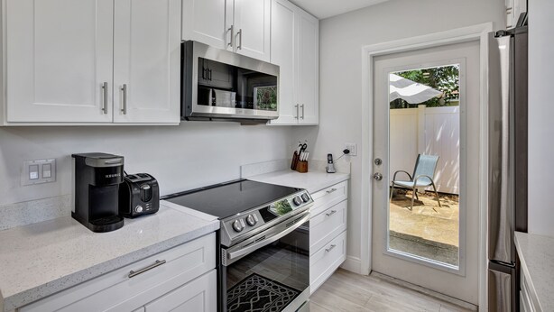 A modern kitchen with white cabinets, a stainless steel stove, and a built-in microwave.