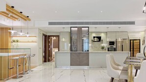 A modern kitchen with a central island, bar stools, and a dining area with a glass table and chairs. - Luxurious 3 bedrooms with Private Sauna & Jacuzzi in the prestigious Korba,Cairo (Cairo Governorate)