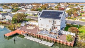 Una propiedad frente al agua con muelle, un porche cubierto y una casa grande con paneles solares.