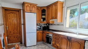 Una cocina con armarios de madera, un refrigerador, una estufa y una ventana.