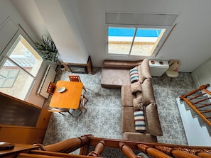 A compact living space with a dining table, sofa, and a staircase.