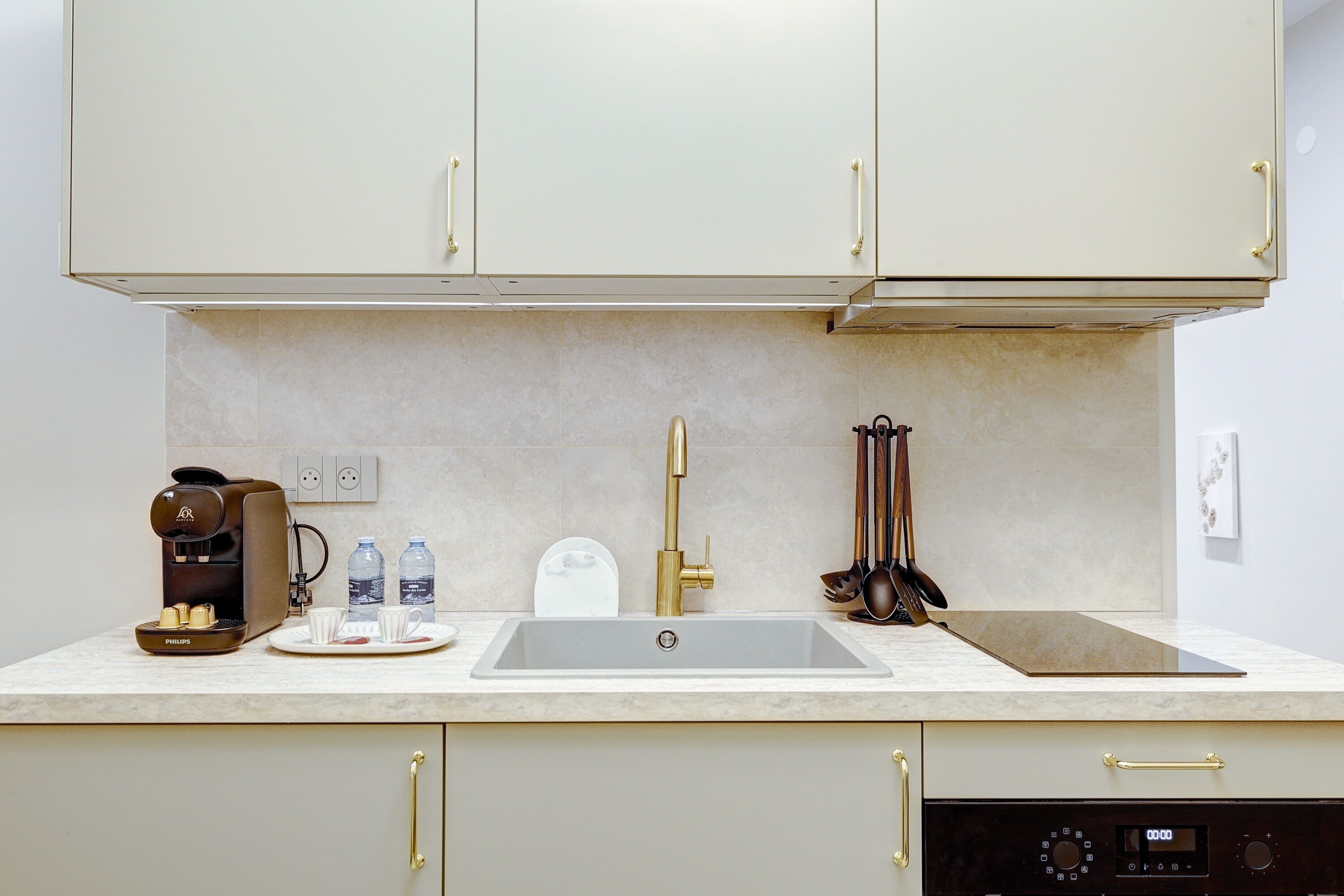 A modern kitchen with a built-in coffee maker, a sink, and a dishwasher.