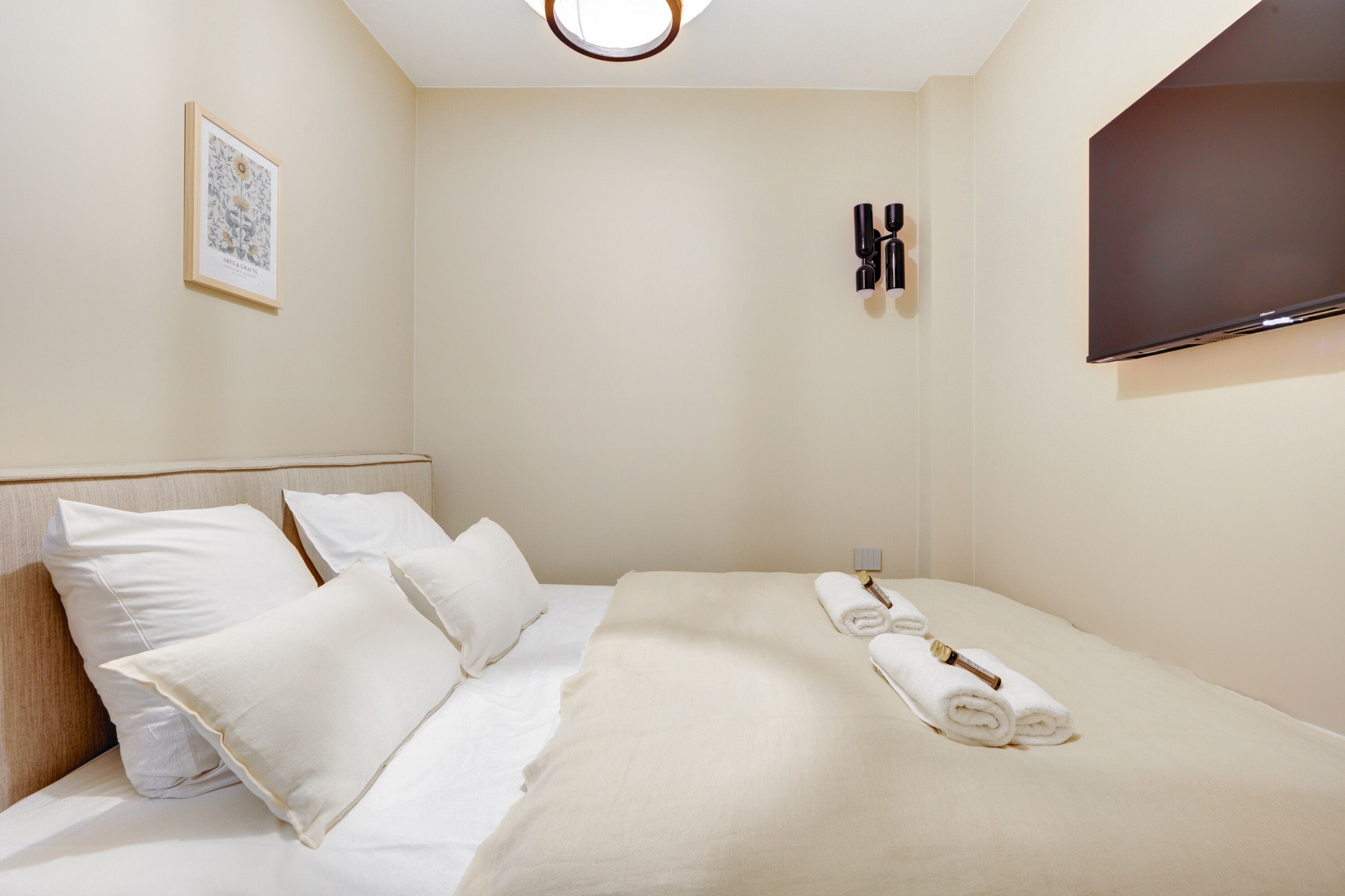Quarto de hotel com cama, almofadas, televisão de tela plana e um quadro na parede.